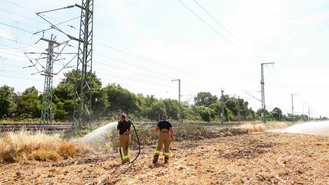 Einsatzkräfte der Feuerwehr löschen einen Brand an der Bahn-Strecke zwischen Düsseldorf und Köln.