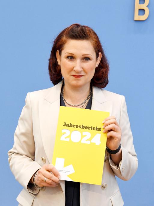 Die unabhängige Antidiskriminierungsbeauftragte des Bundes, Ferda Ataman, hält den Jahresbericht 2024 in die Höhe.