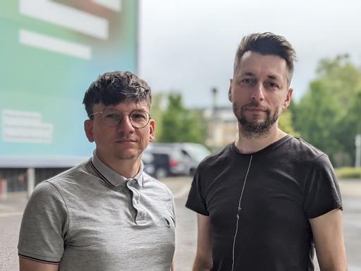 Die Hosts des Podcasts "Ostkinder 80/82" Danny Frede und Alexander Derno stehen vor dem Dlf-Funkhaus in Köln. 