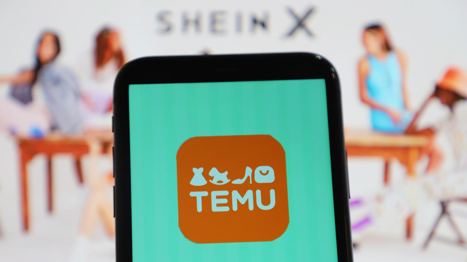 Zu sehen ist ein Smartphone-Bildschirm mit dem Logo der chinesischstämmigen Shopping-Plattform Temu - im Hintergrund verschwommen mehrere Frauen und das Logo des vor allem für Fast Fashion bekannten E-Commerce Unternehmens Shein, das in China gegründet wurde und mittlerweile seinen Sitz in Singapur hat. 