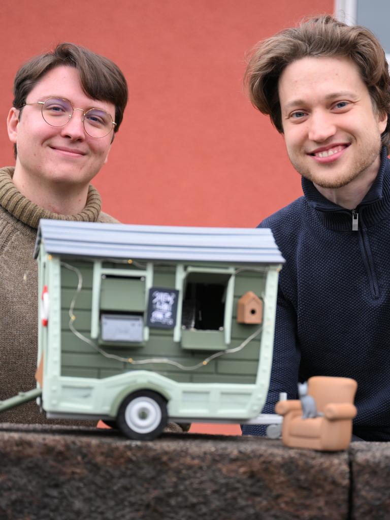 David Zapfe-Wildemann und Raven Rusch von dem Kölner Independent-Gamingstudio Neoludic stehen vor einem Haus, in dem ihre Firma ihren Sitz hat. Vor sich halten sie das Model eines Wohnwagen in Form eines Hauses. David Zapfe-Wildemann und Raven Rusch von dem Kölner Independent-Gamingstudio Neoludic stehen vor einem Haus, in dem ihre Firma ihren Sitz hat. Vor sich halten sie das Model eines Wohnwagen in Form eines Hauses.