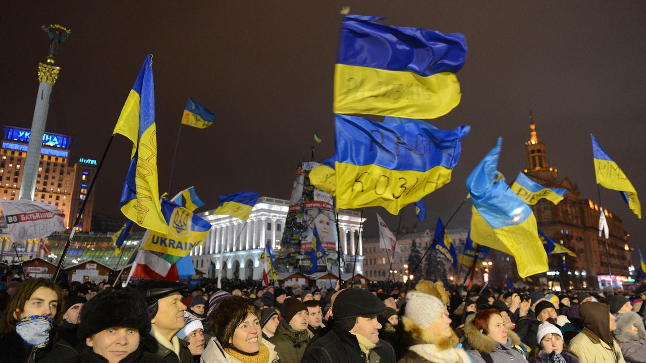 Demonstranten auf dem nächtlichen Maidan-Platz (Unabhängigkeitsplatz) in Kiew schwenken ukrainische Fahnen 