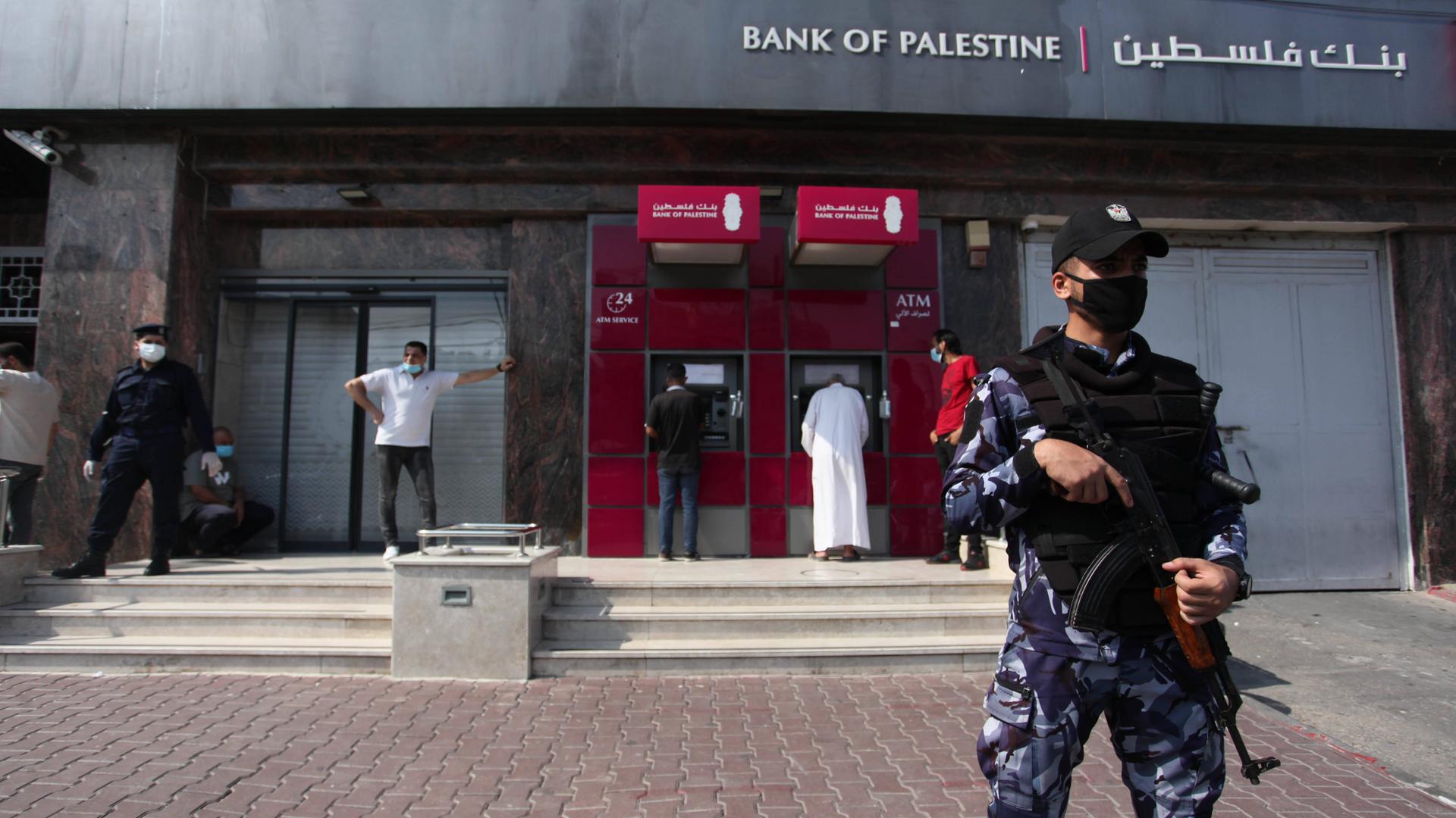 Das Foto zeigt eine Filiale der Bank of Palestine in der Stadt Gaza. Vor dem Gebäude steht Wachpersonal mit einem Maschinengewehr. 