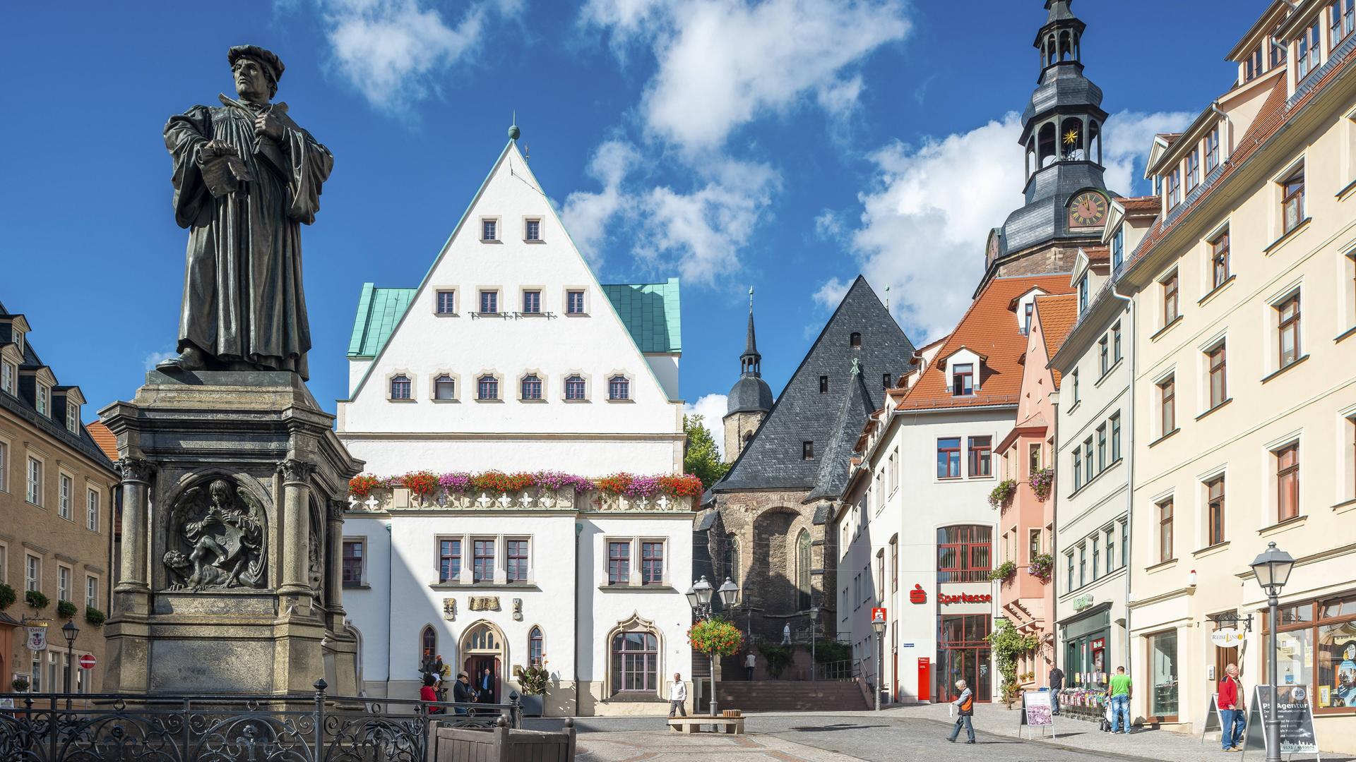 Der Marktplatz von Eisleben mit dem Denkmal für Martin Luther, einer Bronzeplastik von 1883 von Rudolf Siemering, in der Mitte das historische Rathaus, rechts die Andreaskirche