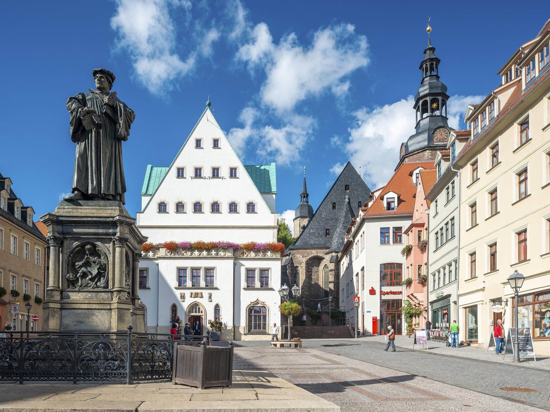 Der Marktplatz von Eisleben mit dem Denkmal für Martin Luther, einer Bronzeplastik von 1883 von Rudolf Siemering, in der Mitte das historische Rathaus, rechts die Andreaskirche