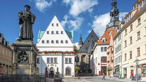 Der Marktplatz von Eisleben mit dem Denkmal für Martin Luther, einer Bronzeplastik von 1883 von Rudolf Siemering, in der Mitte das historische Rathaus, rechts die Andreaskirche