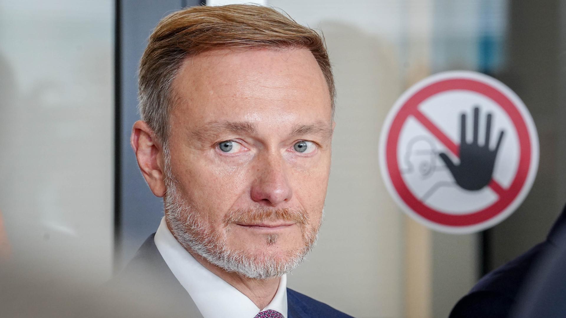 Finanzminister Christian Lindner (FDP) steht im Reichstagsgebäude neben einem Halte-Hinweisschild.