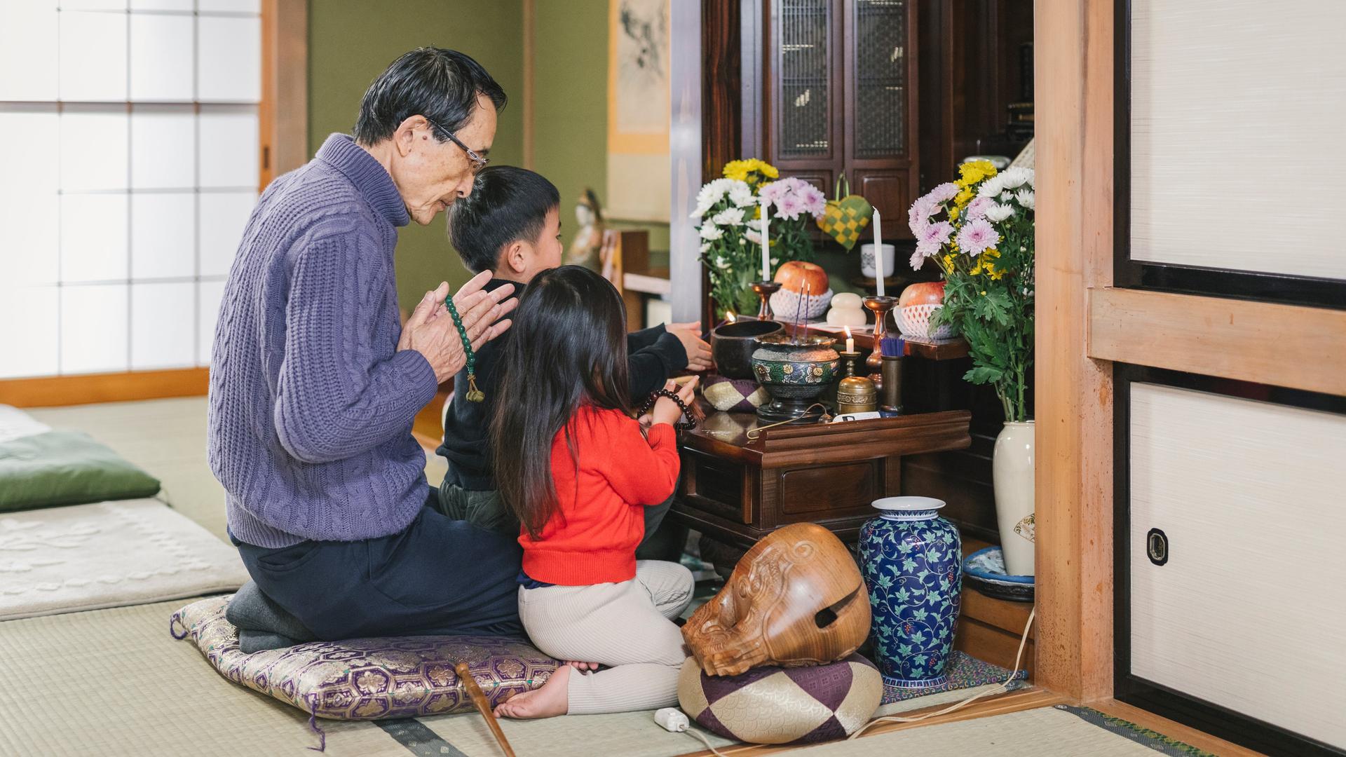 Eine japanische Familie betet vor einem buddhistischem Hausaltar.