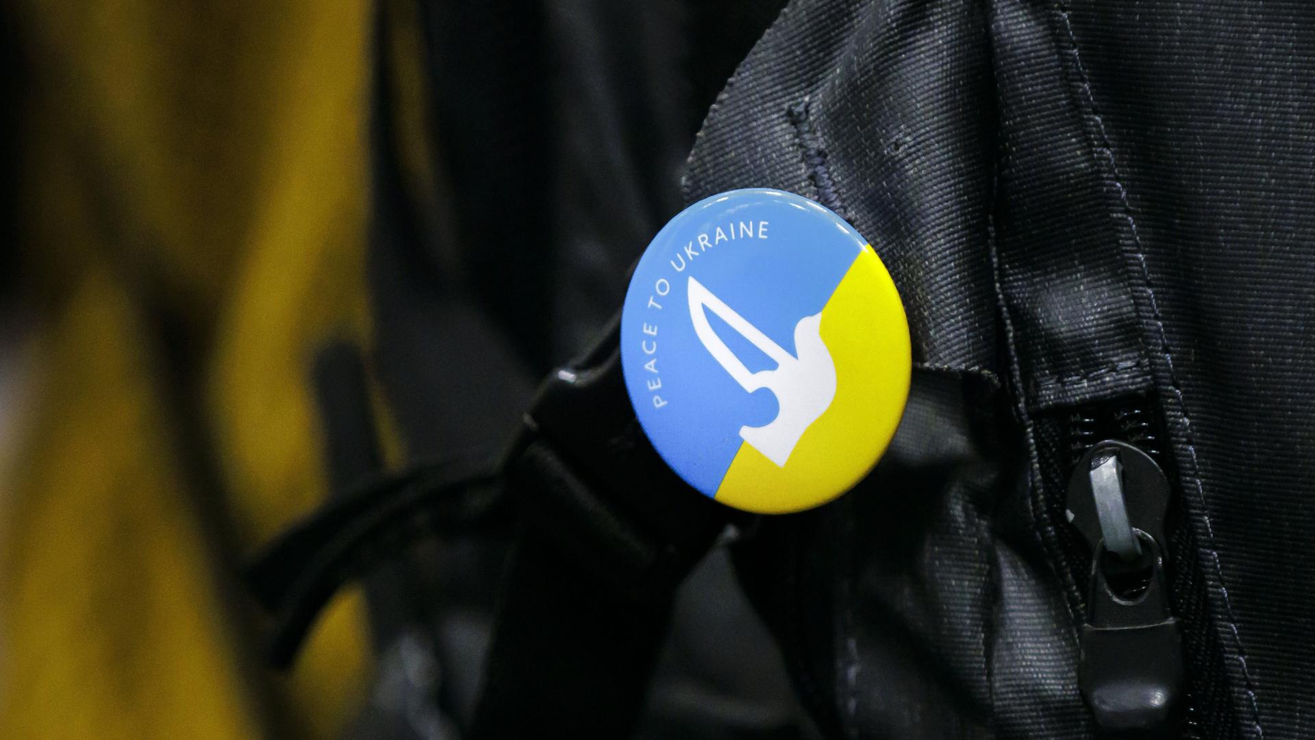 Button mit der Aufschrift "Peace for Ukraine" und einer Friedenstaube auf blau-gelbem Grund