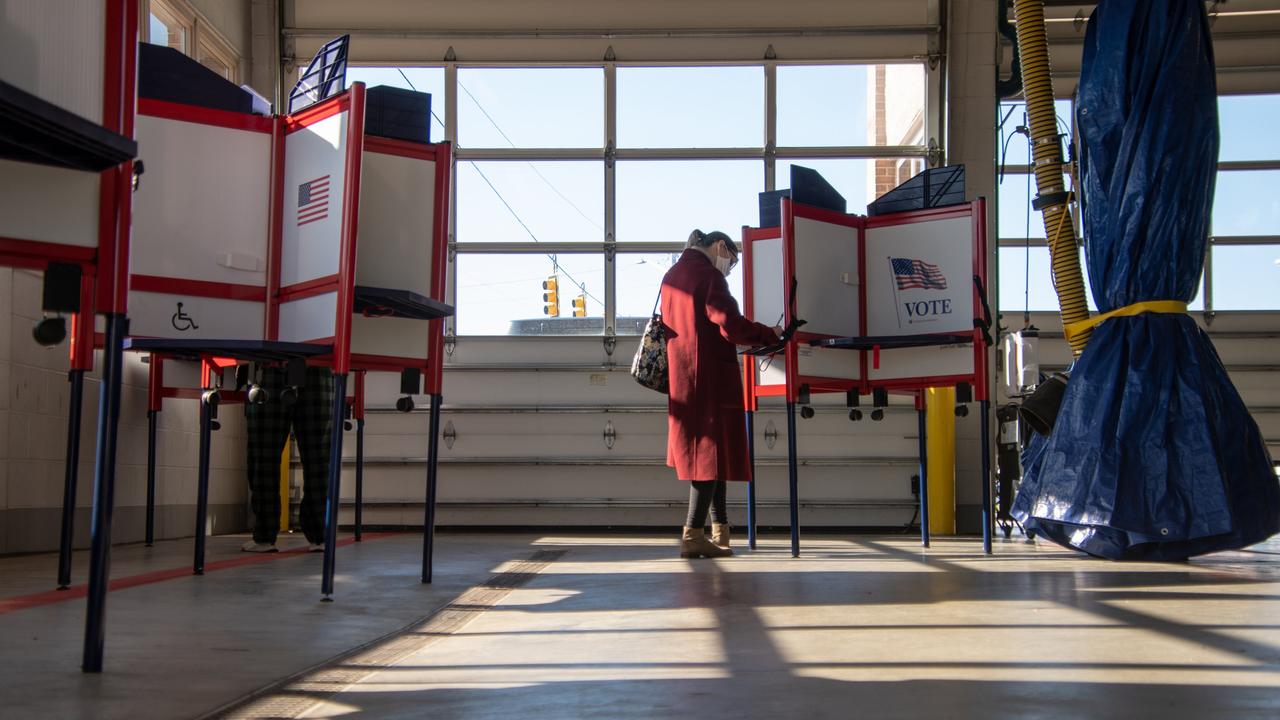 Wählerinnen und Wähler in einem Wahlbüro in Royal Oak, Michigan. Wahlkabinen stehen in einem lichtdurchfluteten Raum.