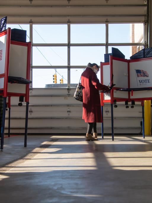 Wählerinnen und Wähler in einem Wahlbüro in Royal Oak, Michigan. Wahlkabinen stehen in einem lichtdurchfluteten Raum.