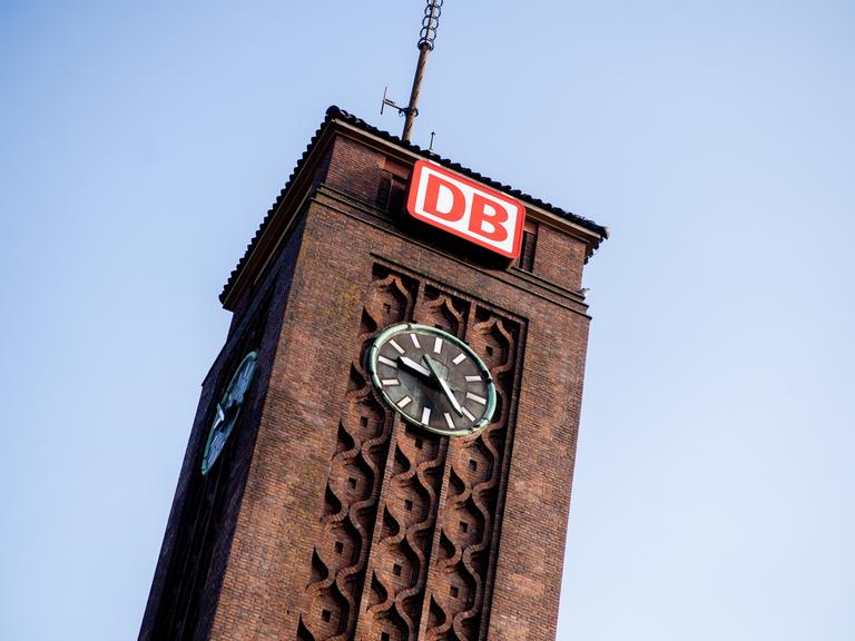 Das Logo der Deutschen Bahn (DB) hängt über einer Uhr am Hauptbahnhof Oldenburg. 