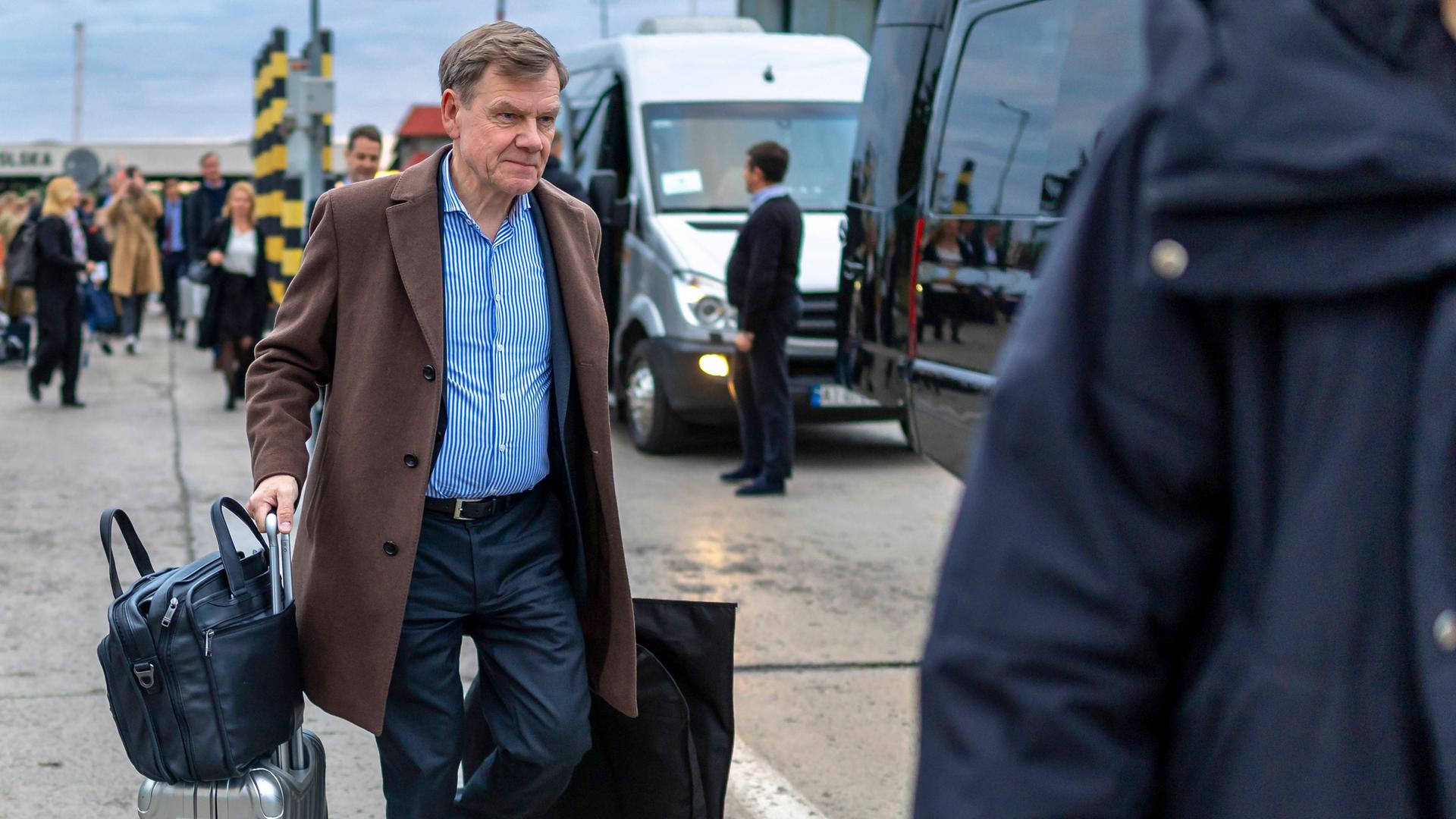 Ein Mann mit Rollkoffer und Tasche.