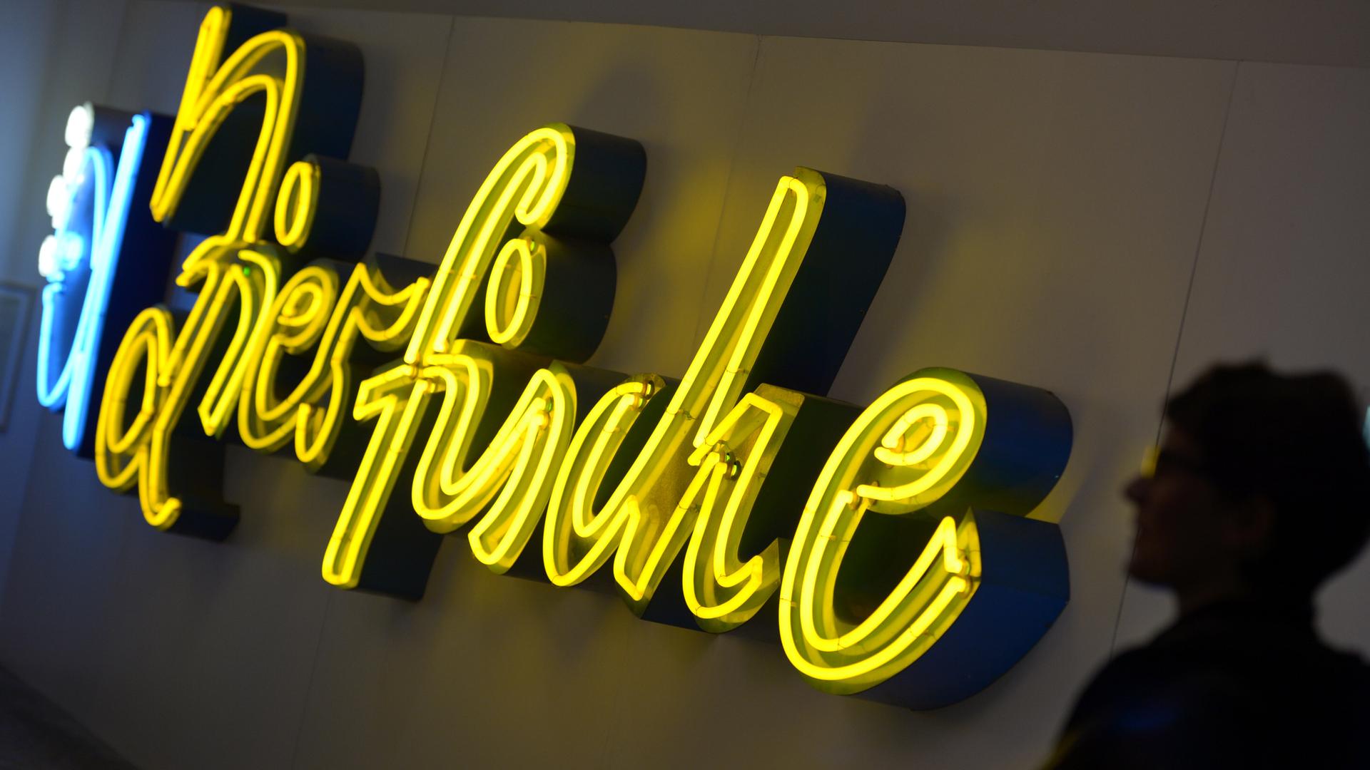 An einer Leuchtreklame, die das Wort "Zierfische" formt, steht eine Besucherin im Buchstaben-Museum in Berlin. An einer Leuchtreklame, die das Wort "Zierfische" formt, steht eine Besucherin im Buchstaben-Museum in Berlin.