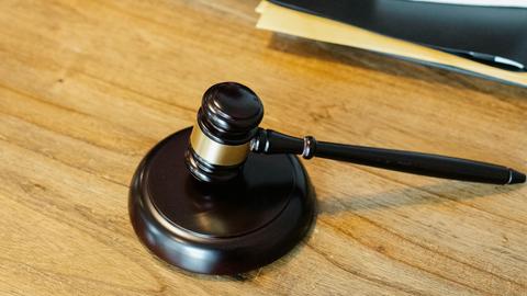 Blick auf einen Tisch, auf dem neben Büchern ein Auktionshammer liegt.