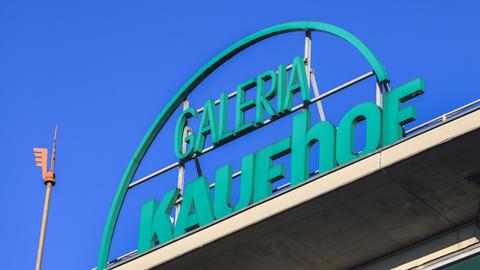 Der Schriftzug "Galeria Kaufhof" aus grünen Buchstaben auf dem Dach einer Filiale unter blauem Himmel