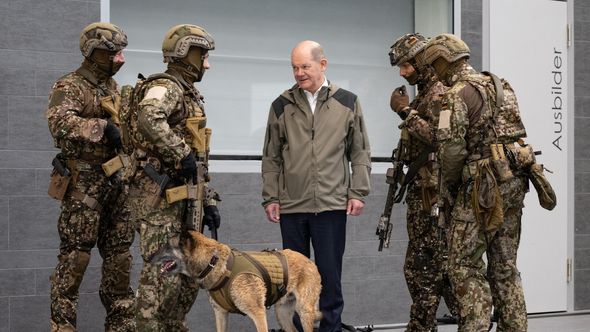 Calw: Bundeskanzler Olaf Scholz (SPD, M) spricht bei einem Besuch des Kommandos Spezialkräfte (KSK) der Bundeswehr mit Soldaten über einen Diensthund.