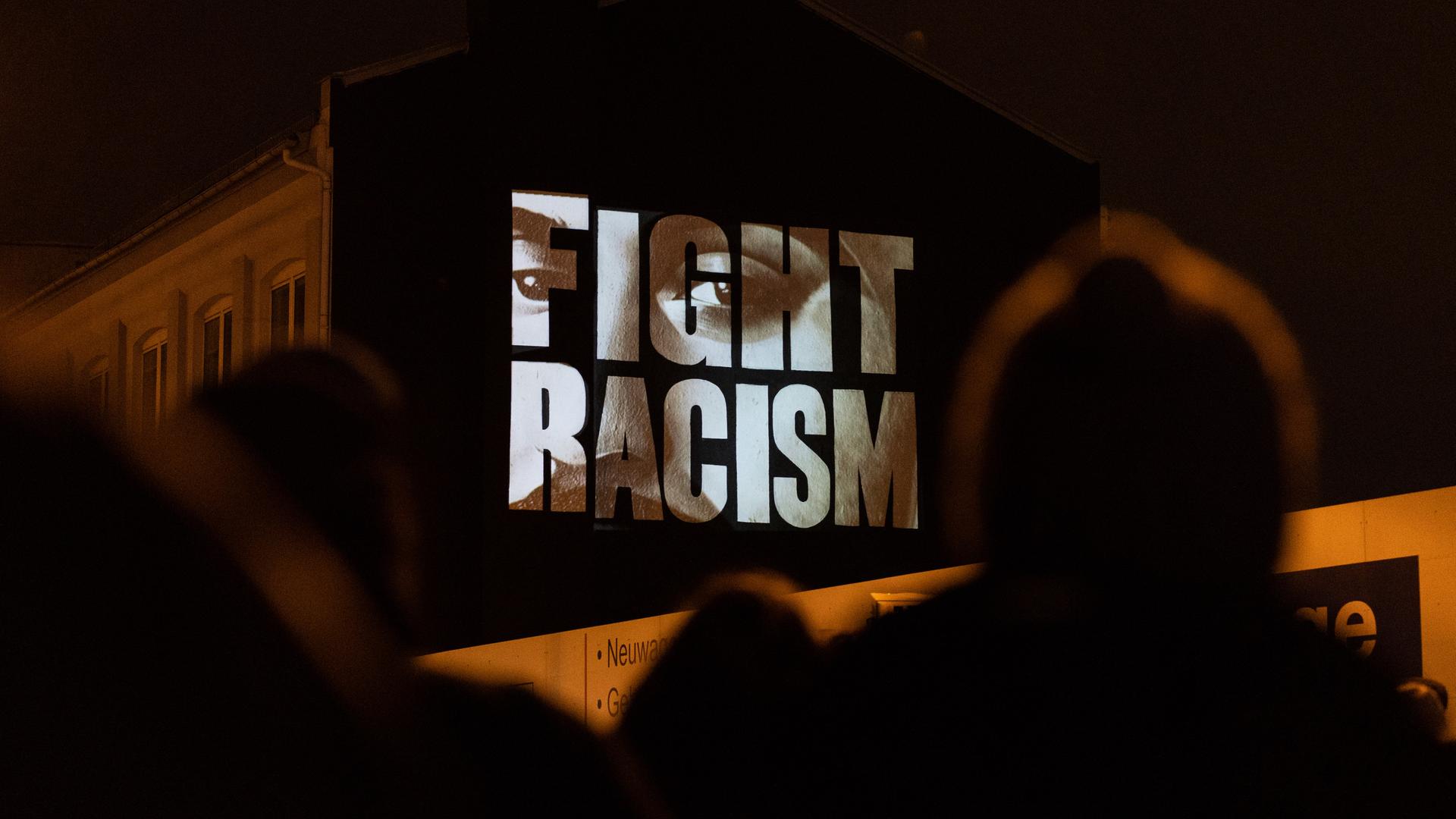 "Fight Racism" mit den Gesichtern der Opfer steht auf einer Hausfassade an der Camberger Brücke zum Gedenken an die Opfer der rassistisch motivierten Anschläge von Hanau im Jahr 2020. Das Künstlerkollektiv "Kollektiv ohne Namen" führte die Aktion durch.