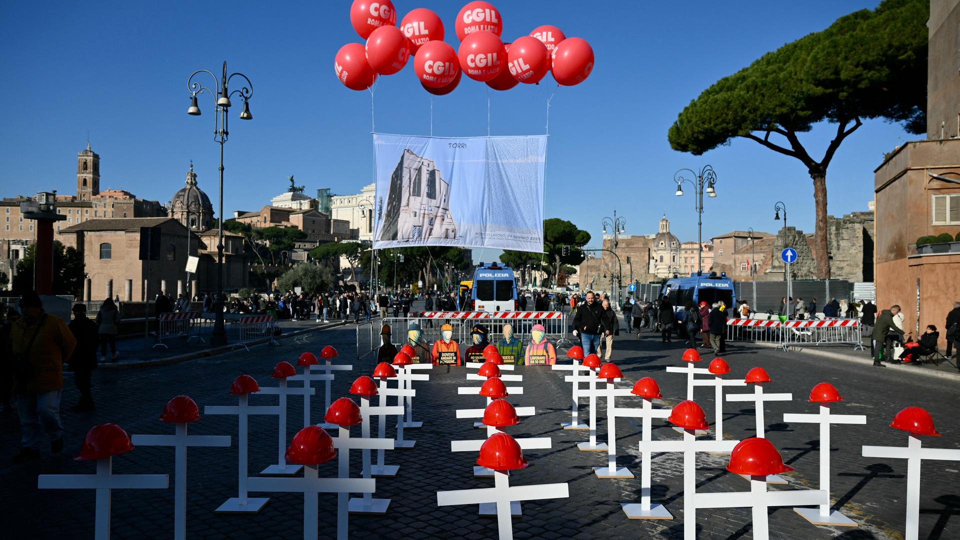 Eine Installation von weißen Kreuzen mit roten Helmen auf der Imperial Forum Avenue in Rom.