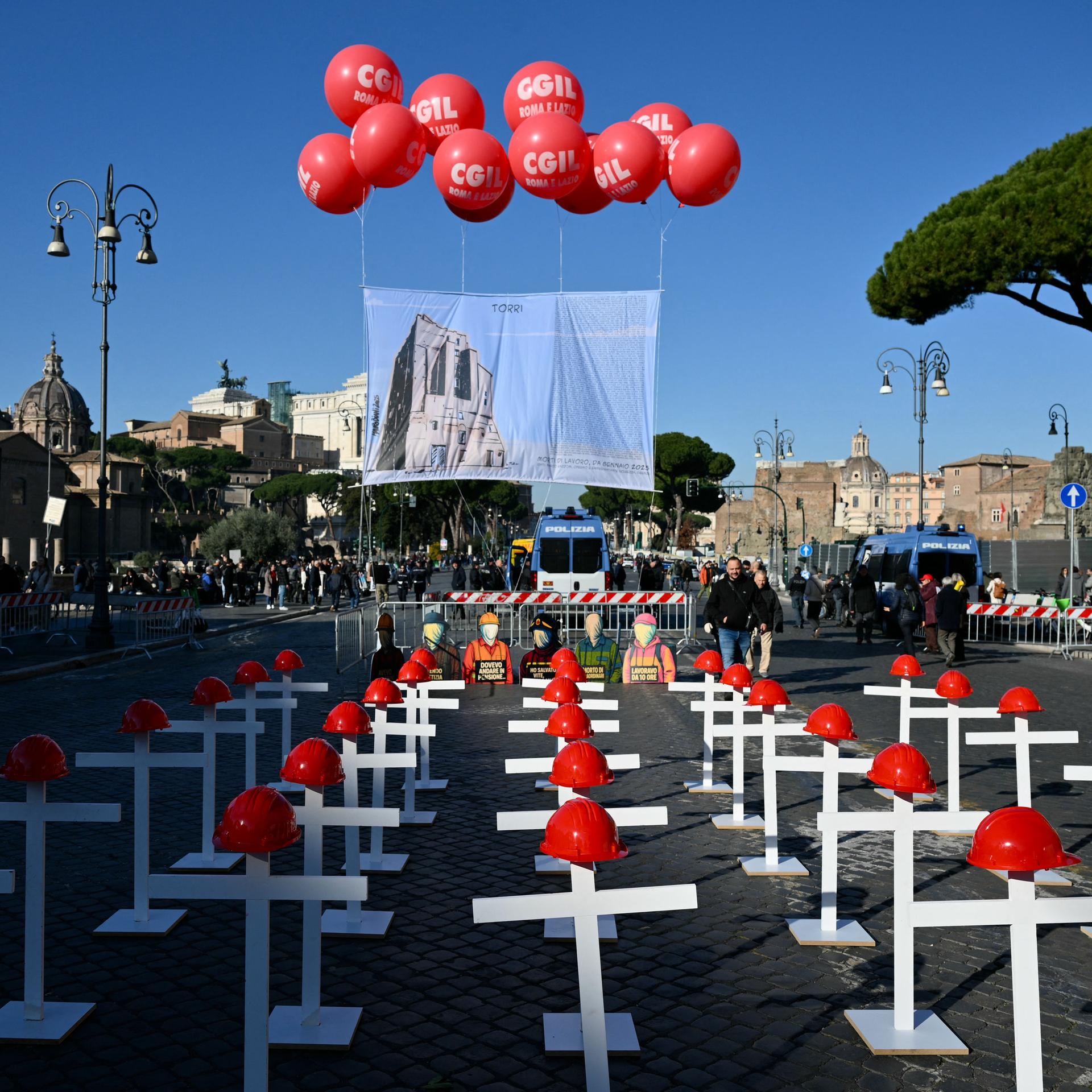 Eine Installation von weißen Kreuzen mit roten Helmen auf der Imperial Forum Avenue in Rom.