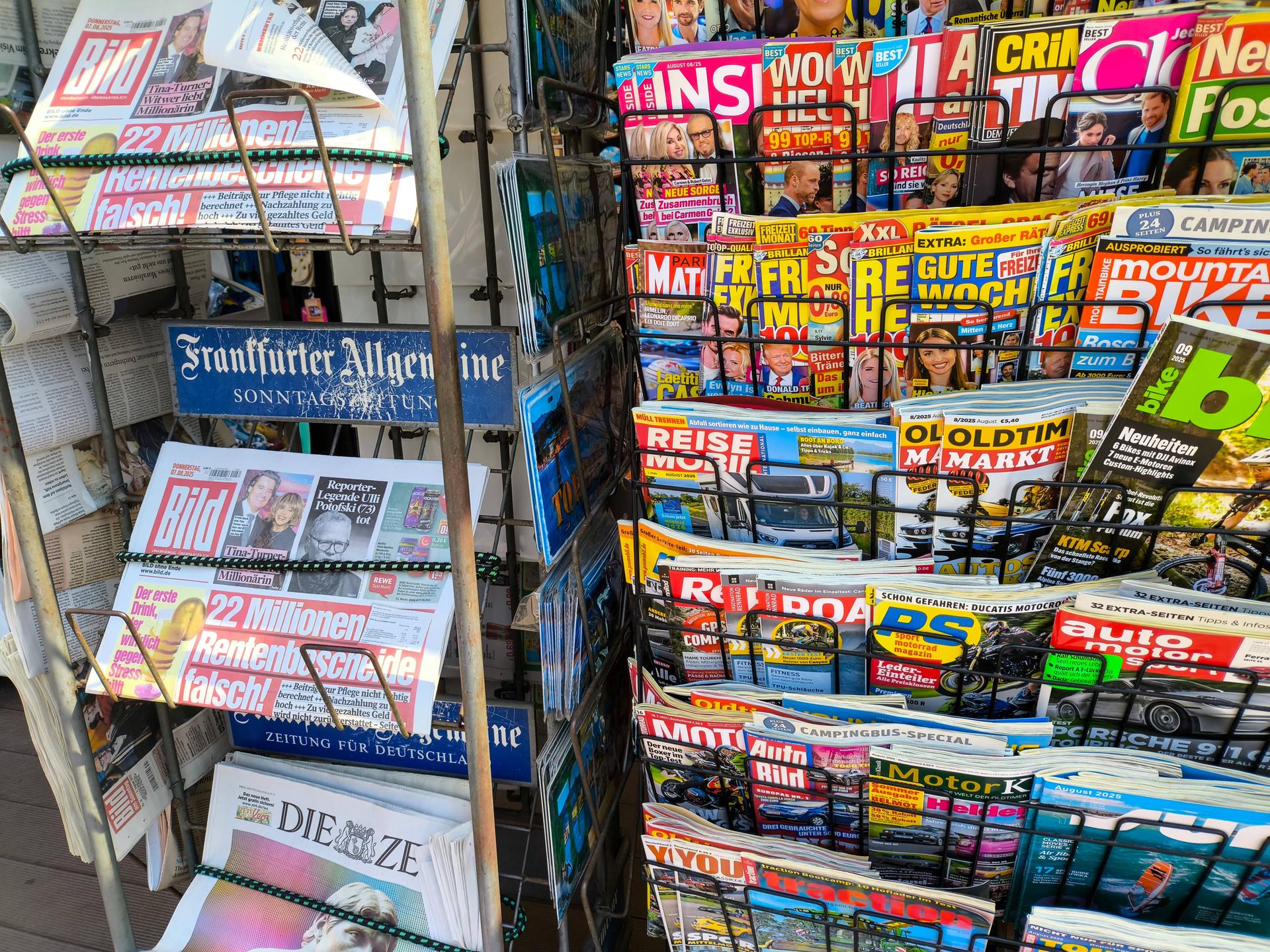 An einem Kiosk sind verschieden Zeitschriften und Zeitungen in Ständern zu sehen An einem Kiosk sind verschieden Zeitschriften und Zeitungen in Ständern zu sehen