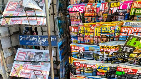 An einem Kiosk sind verschieden Zeitschriften und Zeitungen in Ständern zu sehen An einem Kiosk sind verschieden Zeitschriften und Zeitungen in Ständern zu sehen