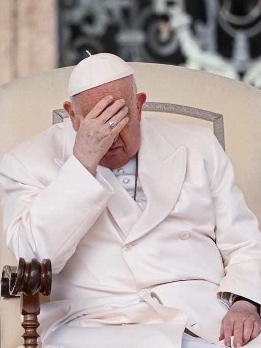 Papst Franziskus sitzt bei der Generalaudienz nachdenklich in seinem Stuhl und stützt den Kopf in die Hand.