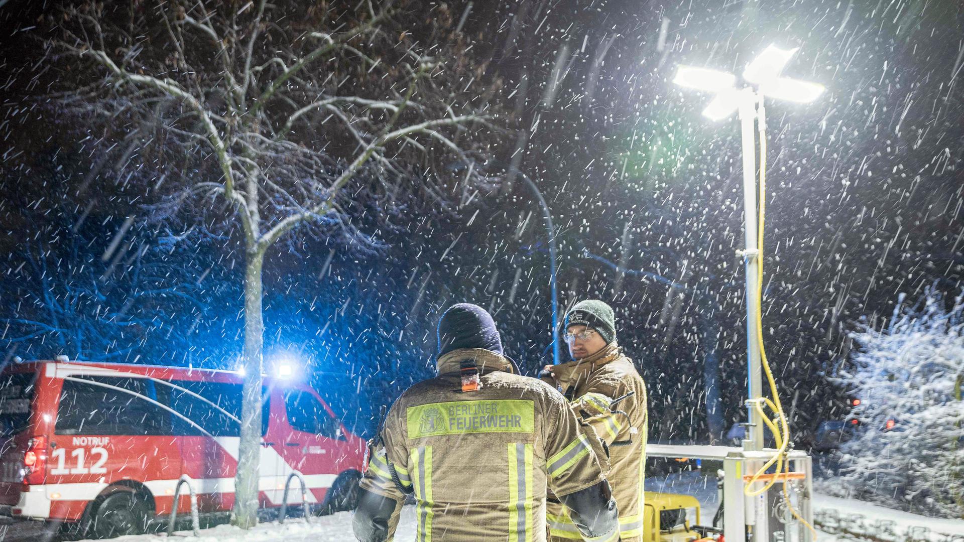 Einsatzkräfte der Berliner Feuerwehr stehen vor einem Generator-Lichtmast an einer Katastrophenschutz-Kontraktstelle vor der Carl-Schuhmann-Sportanlage im Stadtteil Lichterfelde während des Stromausfalls im Januar 2026.