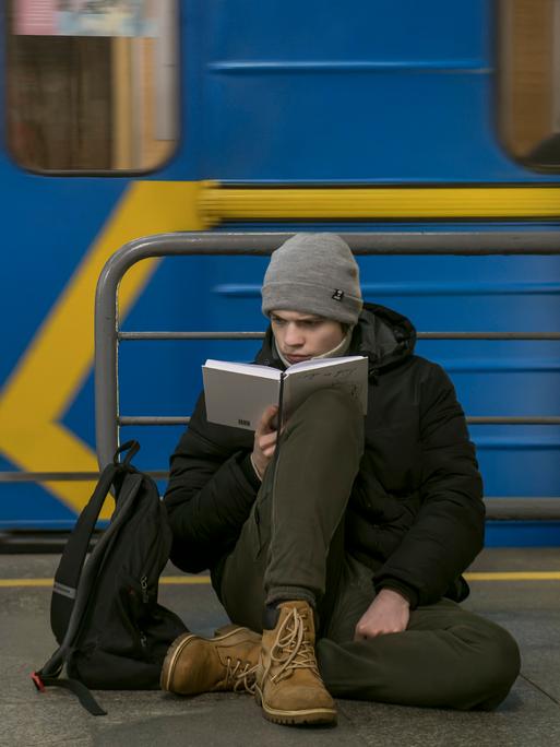 Ein Mann liest, während er in einer U-Bahn-Station in Kiew vor den russischen Luftangriffen Schutz gesucht hat.
