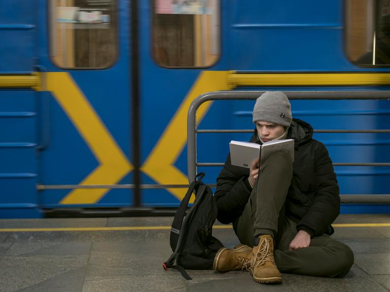 Ein Mann liest, während er in einer U-Bahn-Station in Kiew vor den russischen Luftangriffen Schutz gesucht hat.