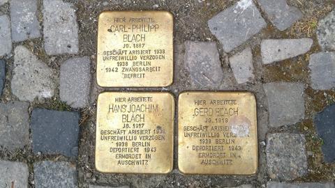 Drei glänzend polierte Stolpersteine im Kopfsteinpflaster. Sie erinnern an Familie Blach.