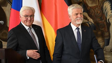 Bundespräsident Frank-Walter Steinmeier und Petr Pavel, Präsident der Tschechischen Republik, bei einer gemeinsamen Pressekonferenz in Prag. Sie lachen. Hinter ihnen die Flaggen Deutschlands und Tschechiens. 