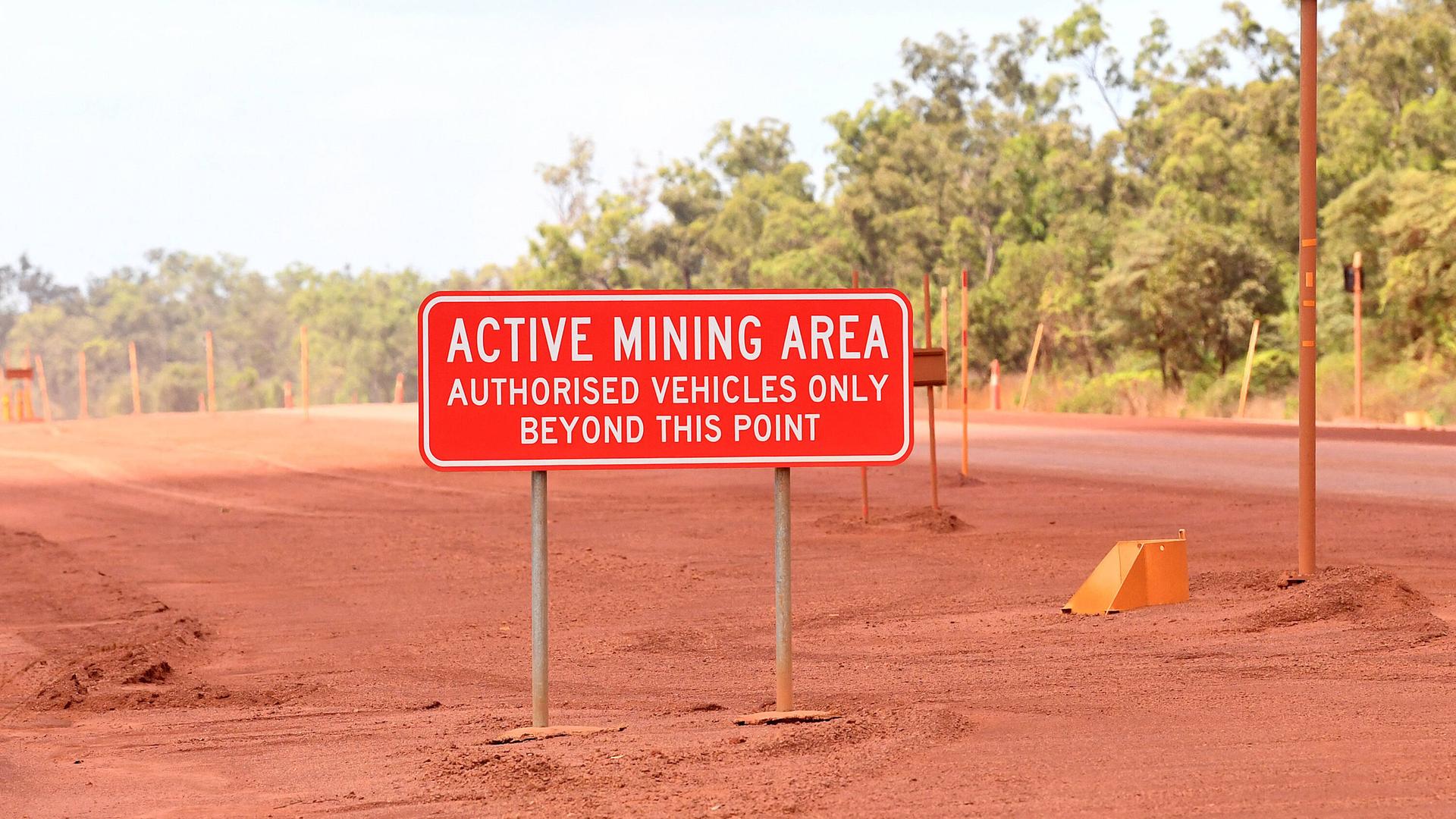 Ein Schild mit der Aufschrift "Active Mining Area - Authorized Vehicles Bexond This Point" vor einer Bauxit-Mine in Australien.
