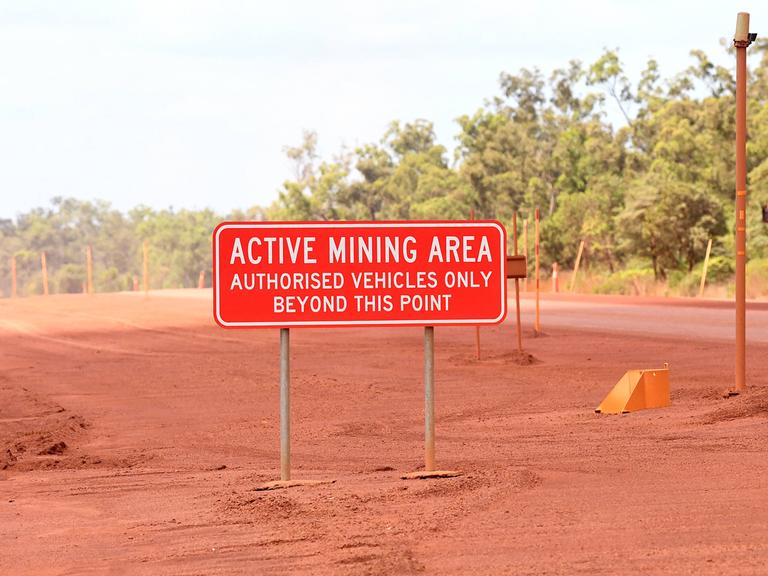 Ein Schild mit der Aufschrift "Active Mining Area - Authorized Vehicles Bexond This Point" vor einer Bauxit-Mine in Australien.