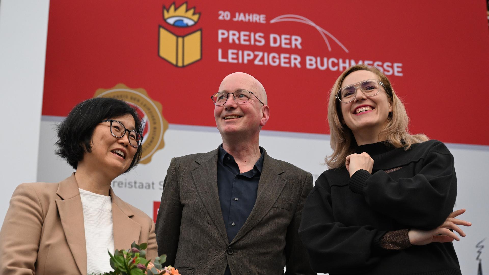 Die Preisträger der Leipziger Buchmesse Ki-Hyang Lee (li), Tom Holert und Barbi Marković stehen auf einer Bühne