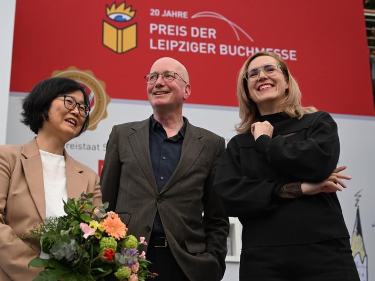 Die Preisträger der Leipziger Buchmesse Ki-Hyang Lee (li), Tom Holert und Barbi Marković stehen auf einer Bühne