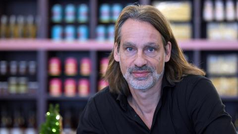 Richard David Precht blickt vor unscharfem Bildhintergrund ernst in die Kamera
