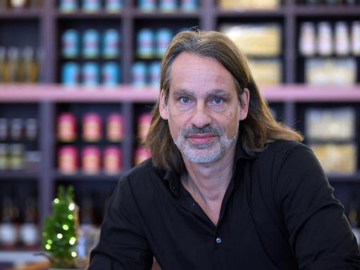 Richard David Precht blickt vor unscharfem Bildhintergrund ernst in die Kamera