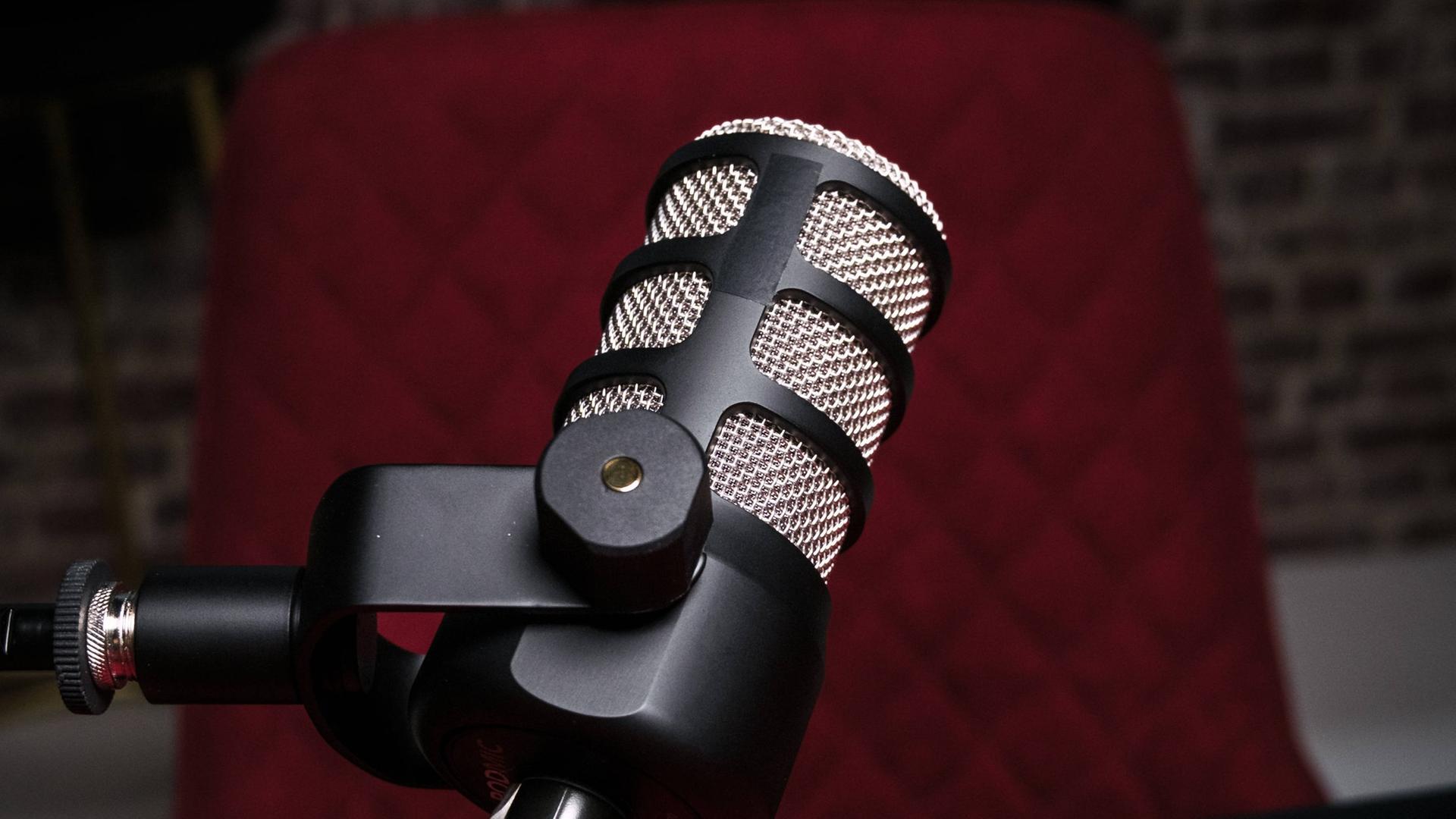 Vor einem Bürostuhl hängt ein Mikrofon in einem Studio