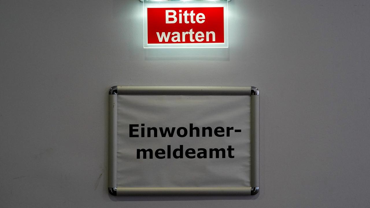 Über dem Schild "Einwohnermeldeamt" leuchtet der Schriftzug "Bitte warten".