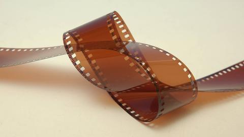 Analoger Kleinbild-Filmstreifen verknotet auf gelblichen Untergrund.