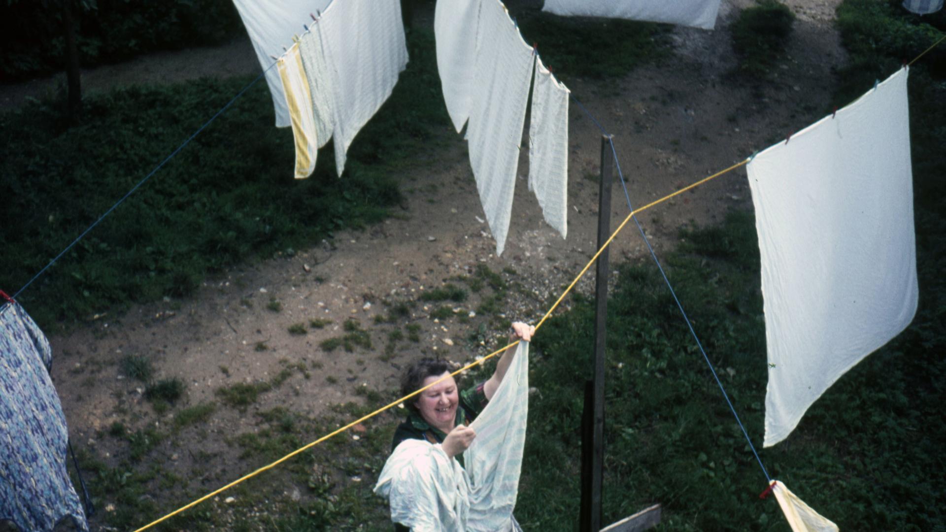 1960er Jahre: Eine Frau hängt Wäsche an einer Wäscheleine draußen auf.