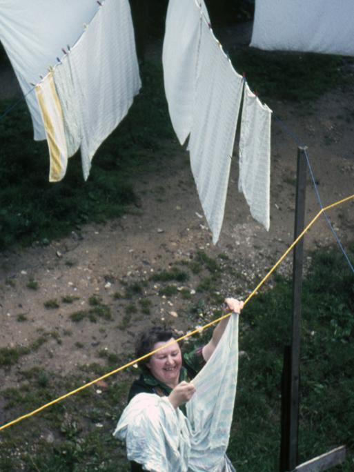 1960er Jahre: Eine Frau hängt Wäsche an einer Wäscheleine draußen auf.