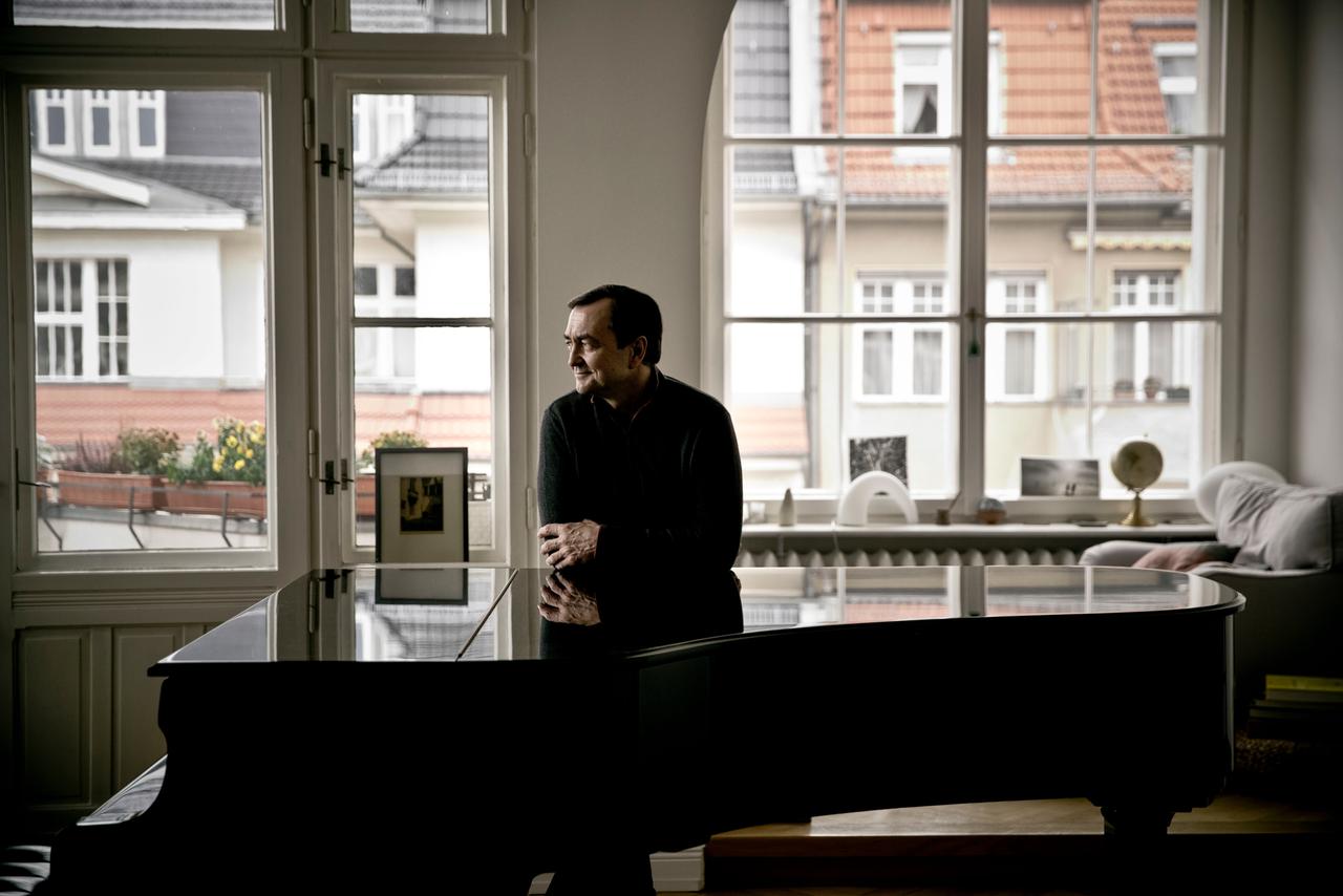 Pierre-Laurent Aimard lehnt in seiner Berliner Wohnung auf seinem geschlossenen Flügel und schaut freundlich zur Seite.