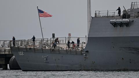 US-Soldaten stehen auf einem Kriegsschiff, die US-Flagge weht an einem kleinen Mast.