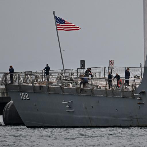 US-Soldaten stehen auf einem Kriegsschiff, die US-Flagge weht an einem kleinen Mast.
