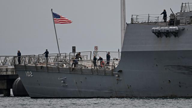US-Soldaten stehen auf einem Kriegsschiff, die US-Flagge weht an einem kleinen Mast.