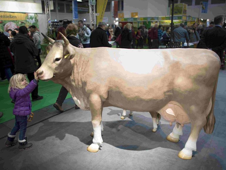Ein Mädchen streichelt eine aufgestellte Kuh bei der Grünen Woche 2018 in Berlin