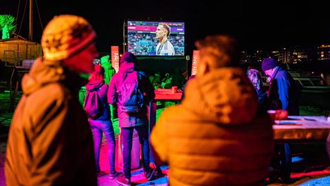 Einige wenige in dicke Jacken gekleidete Menschen beim Public Viewing der WM in einer Strandbar in Magdeburg