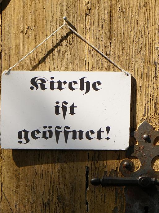 "Kirche ist geöffnet" steht auf dem Schild an einer Kirchentür